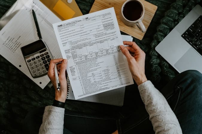Hands completing tax forms after meeting the substantial presence test threshold