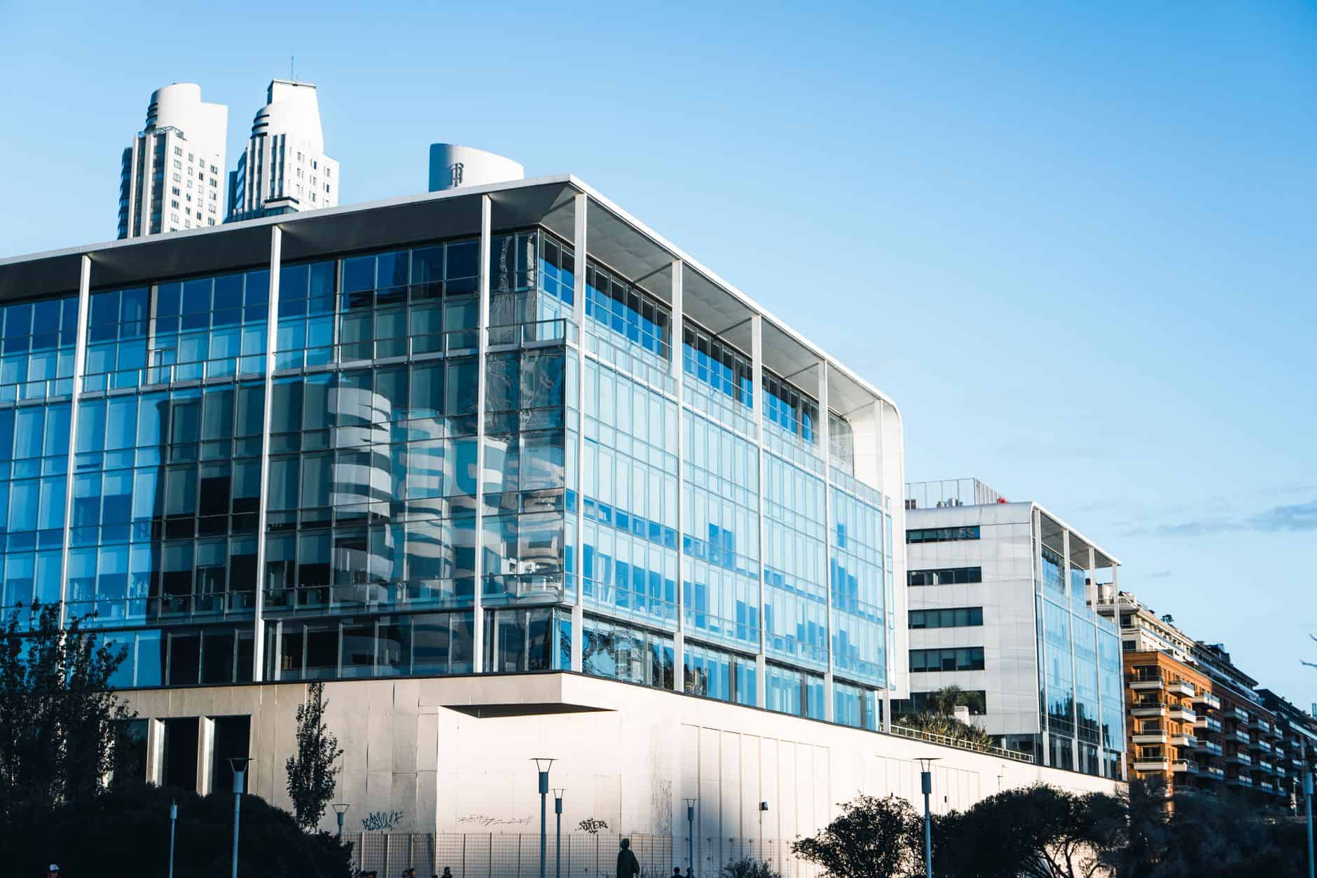 Modern glass office building reflecting exchange rate documentation for international service firms