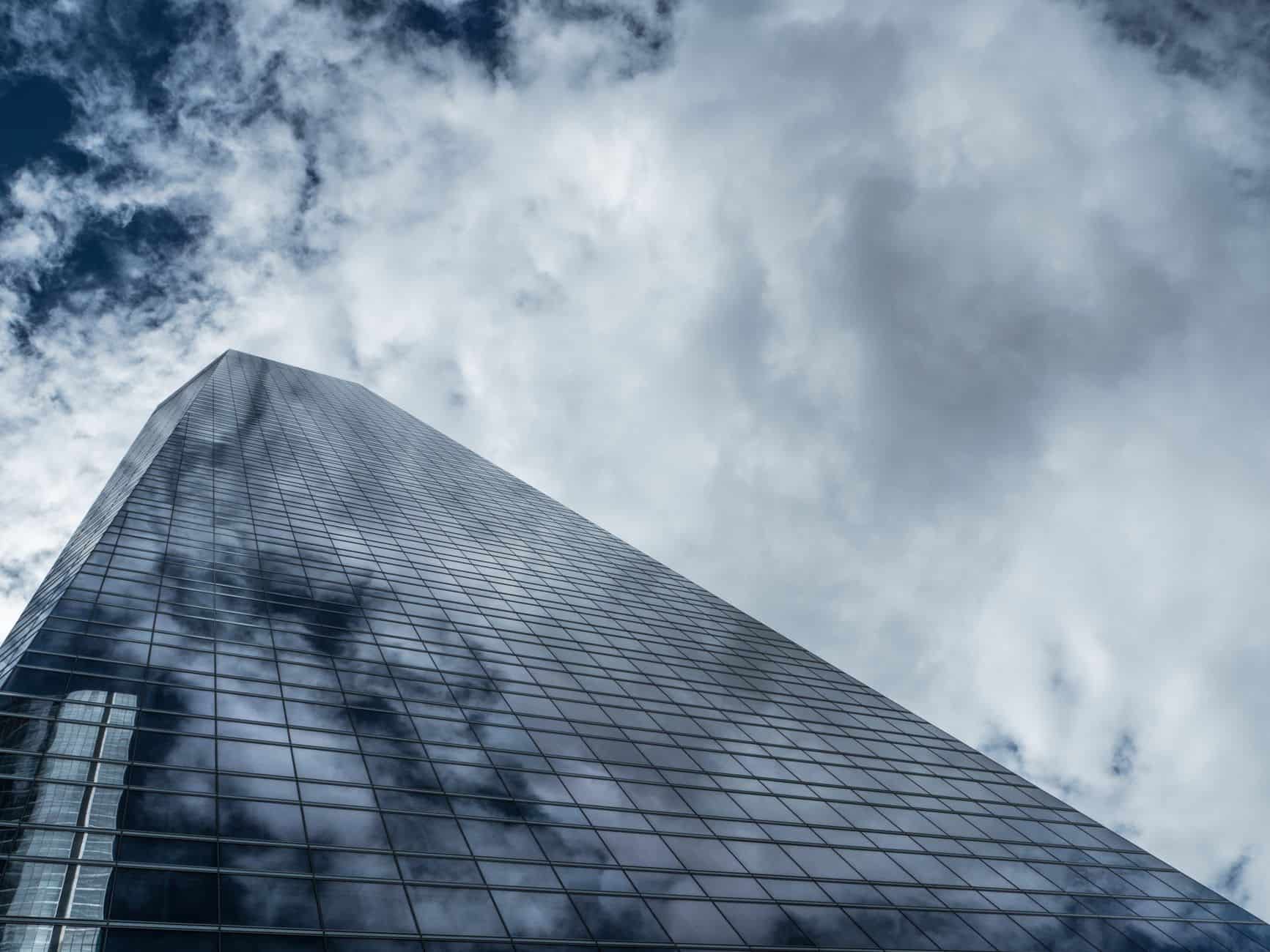 Glass skyscraper reflecting clouds symbolizing corporate compliance obligations in Malaysia